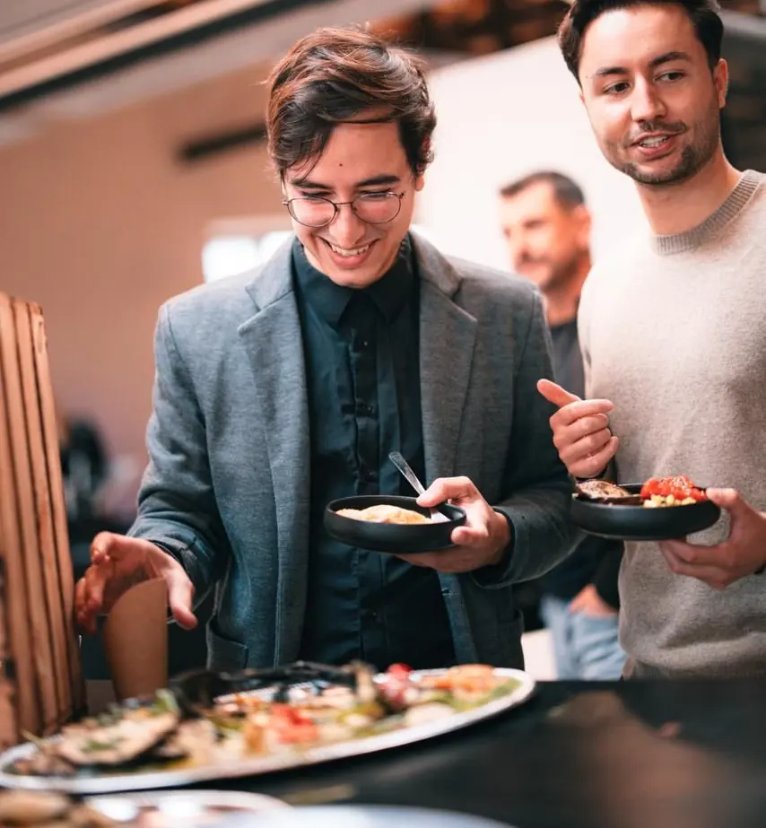 Zwei Gäste mit gefüllten Tellern am Buffet