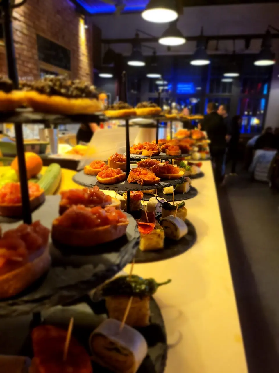 Buffet mit Etageren und Fingerfood in einer blau beleuchteten Eventlocation