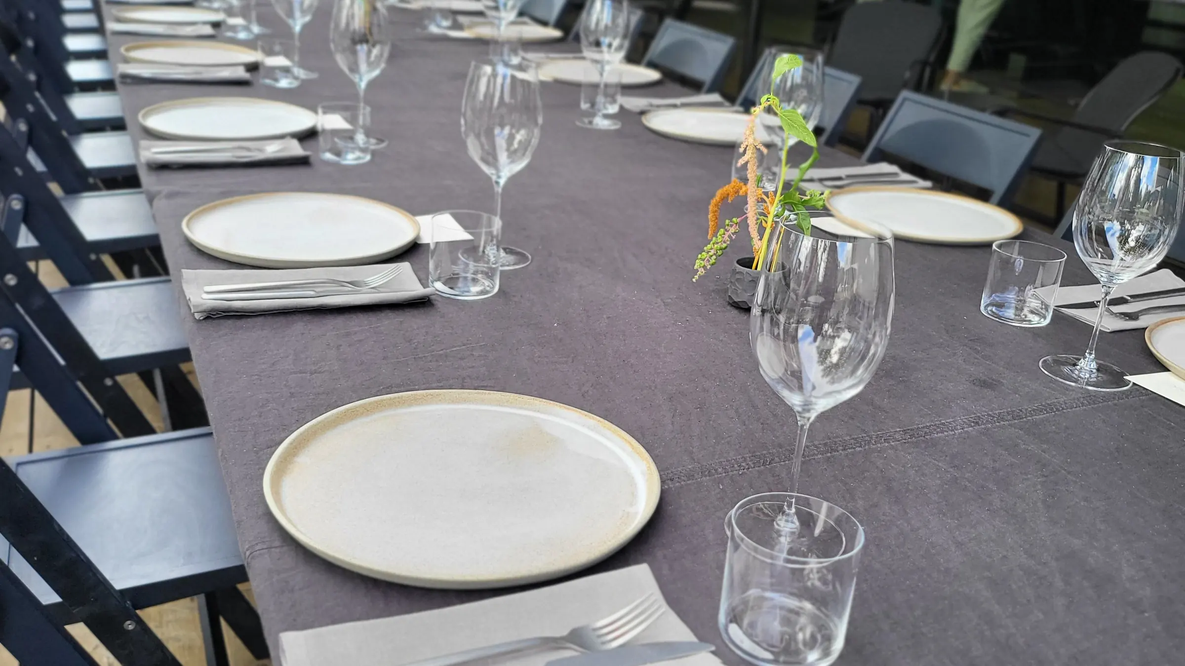 Lange eingedeckte Banketttafel mit Gläsern, Besteck und grauer Tischwäsche