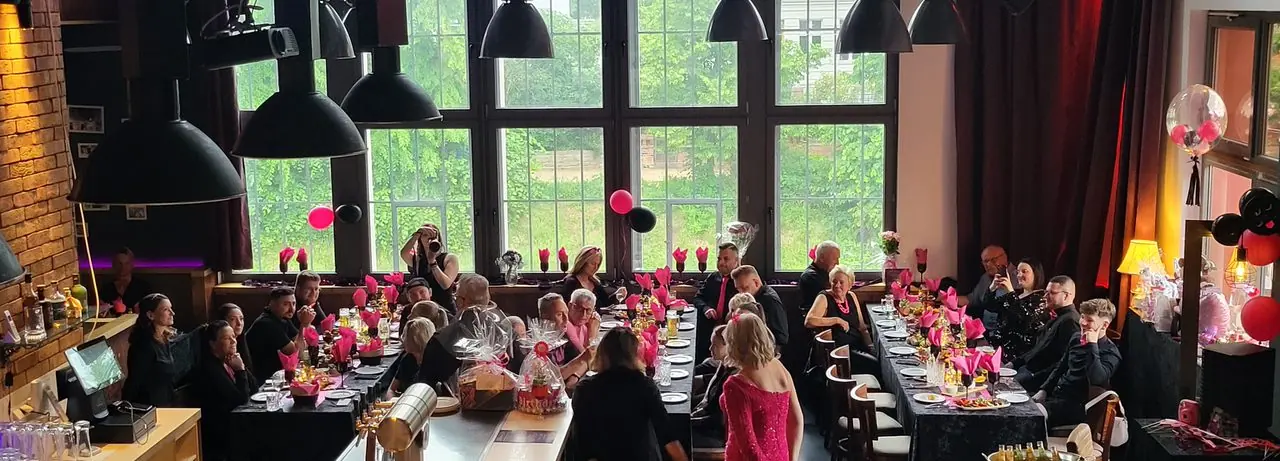 Festlich dekorierte Tafeln mit pinken Servietten und Gästen bei einer privaten Feier